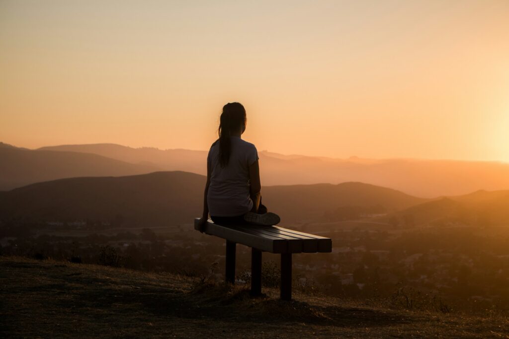 woman contemplating life watching a sunset on a mountain